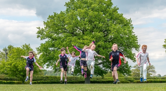 Children jumping for joy in front of the oak tree at Great Walstead